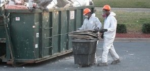 Water Damage Restoration Technicians Removing Moldy Debris To Street Dumpster